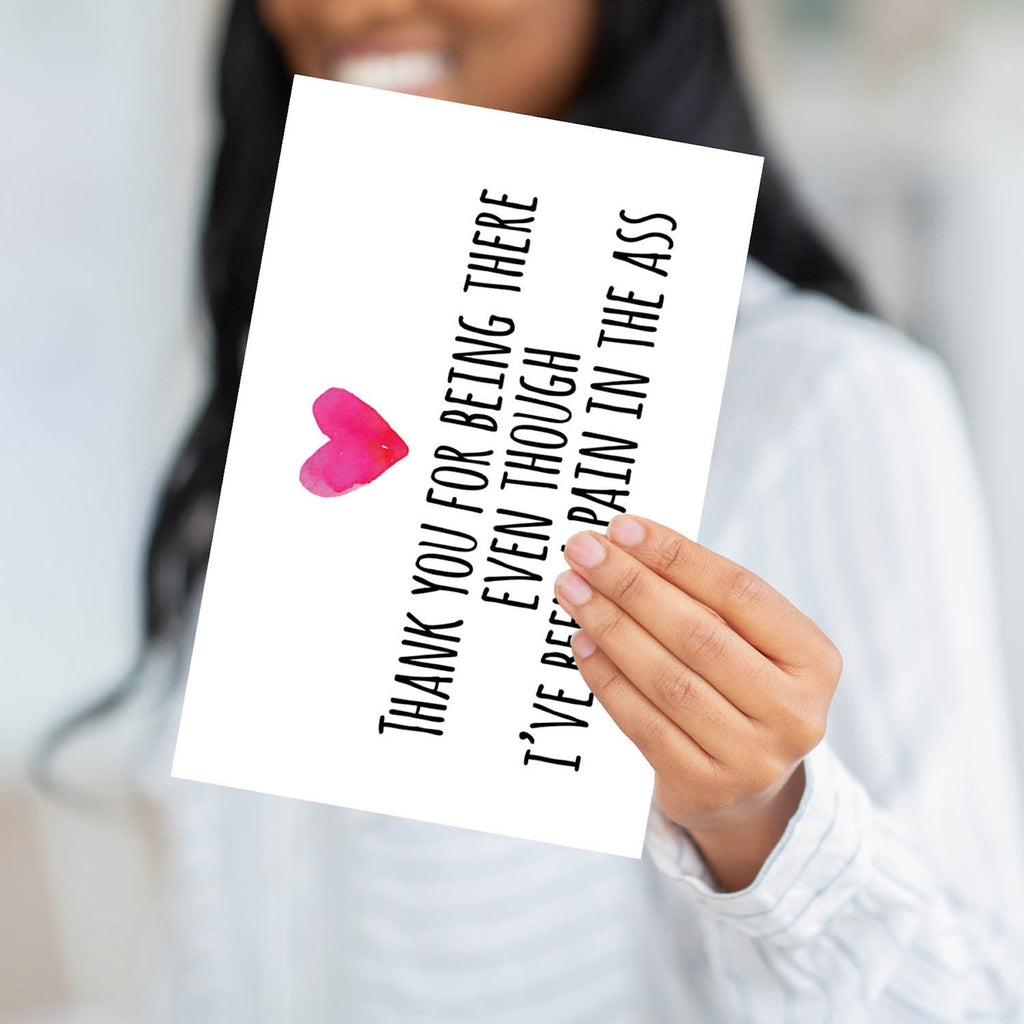 A person holding the "Pain in the Ass" card to demonstrate the professional weight and large scale of the product.