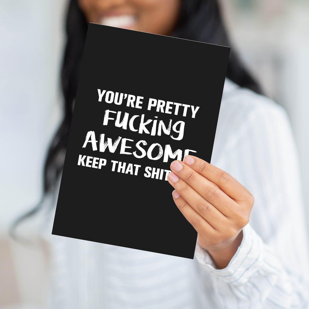A person holding the bold "F*cking Awesome" card to demonstrate the professional weight and large scale of the product.